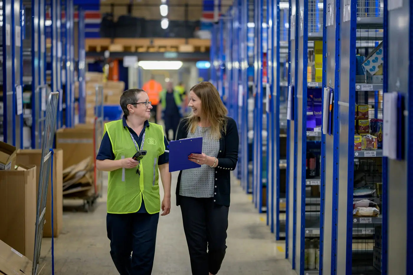 Two warehouse team members checking stock with a scanner and clipboard
